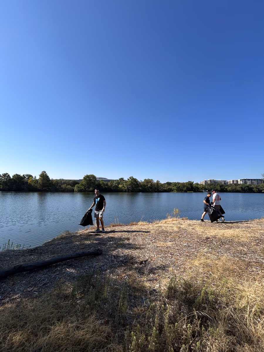 Volunteers picking up trash along the water at the East Austin community clean up
