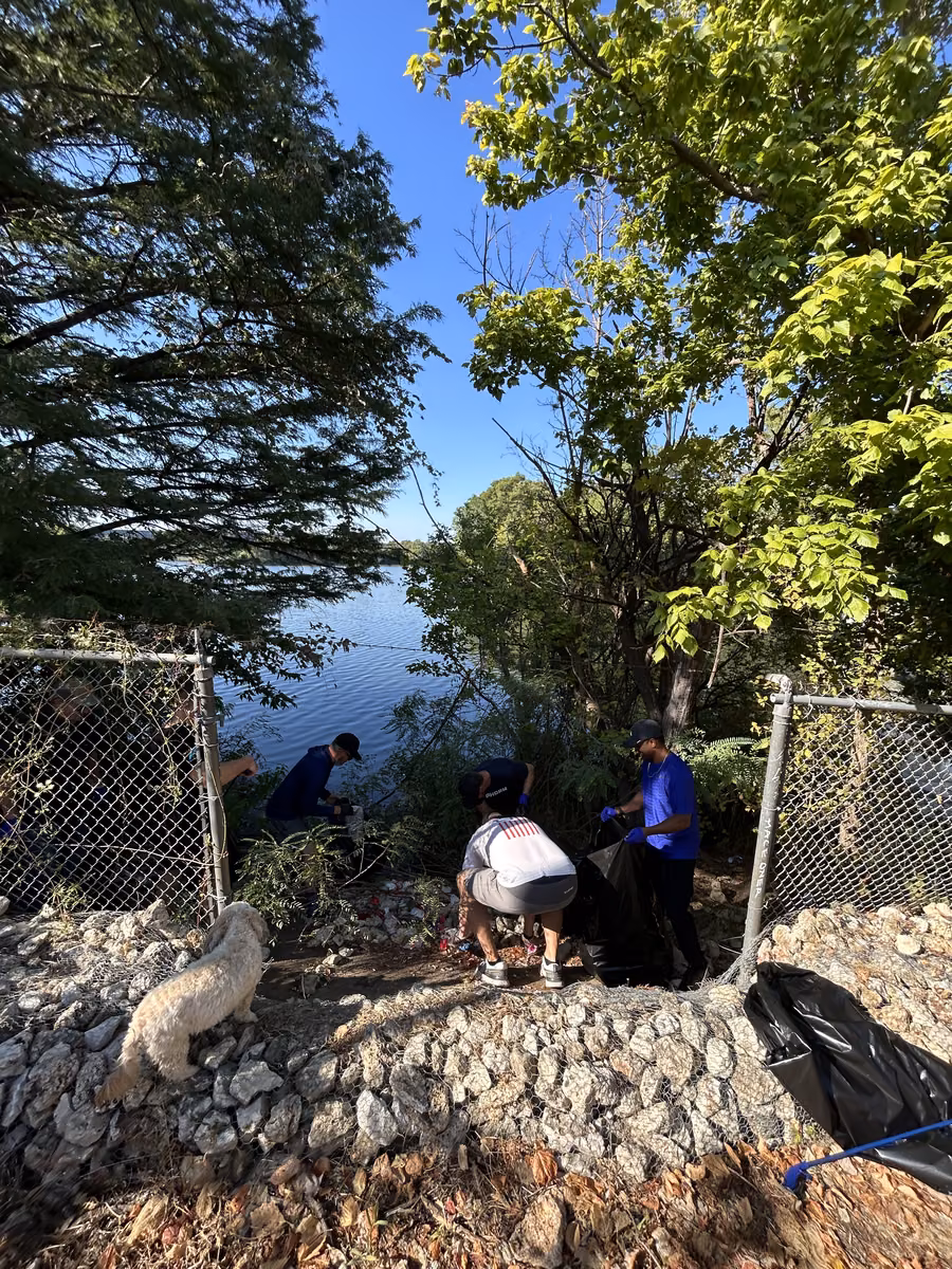 Volunteers clearing trash by the fence line during the East Austin community clean up
